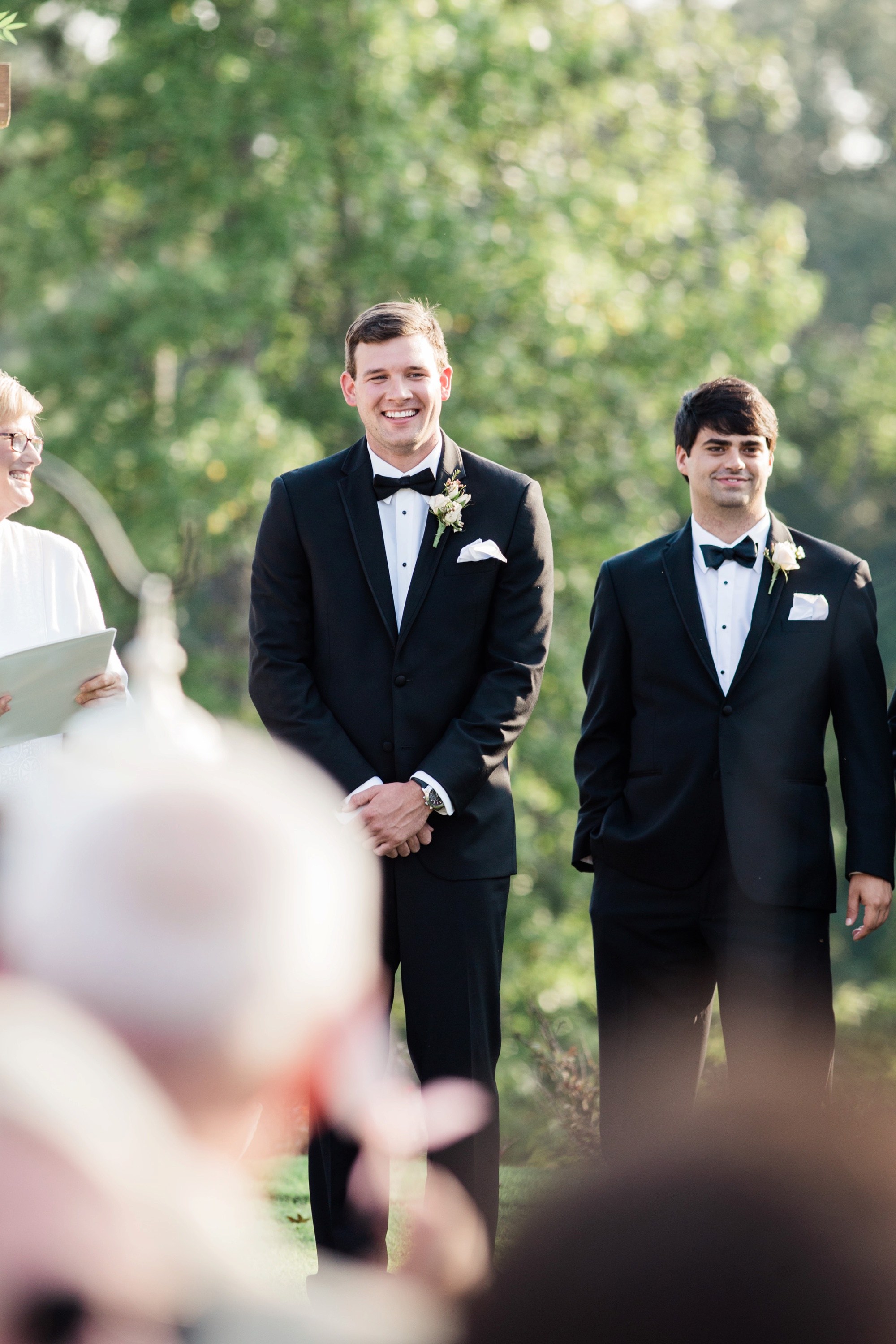 Groom joyfully awaits his bride at the end of the aisle at Foxhall Sporting Club. Photo by Rebecca Cerasani.