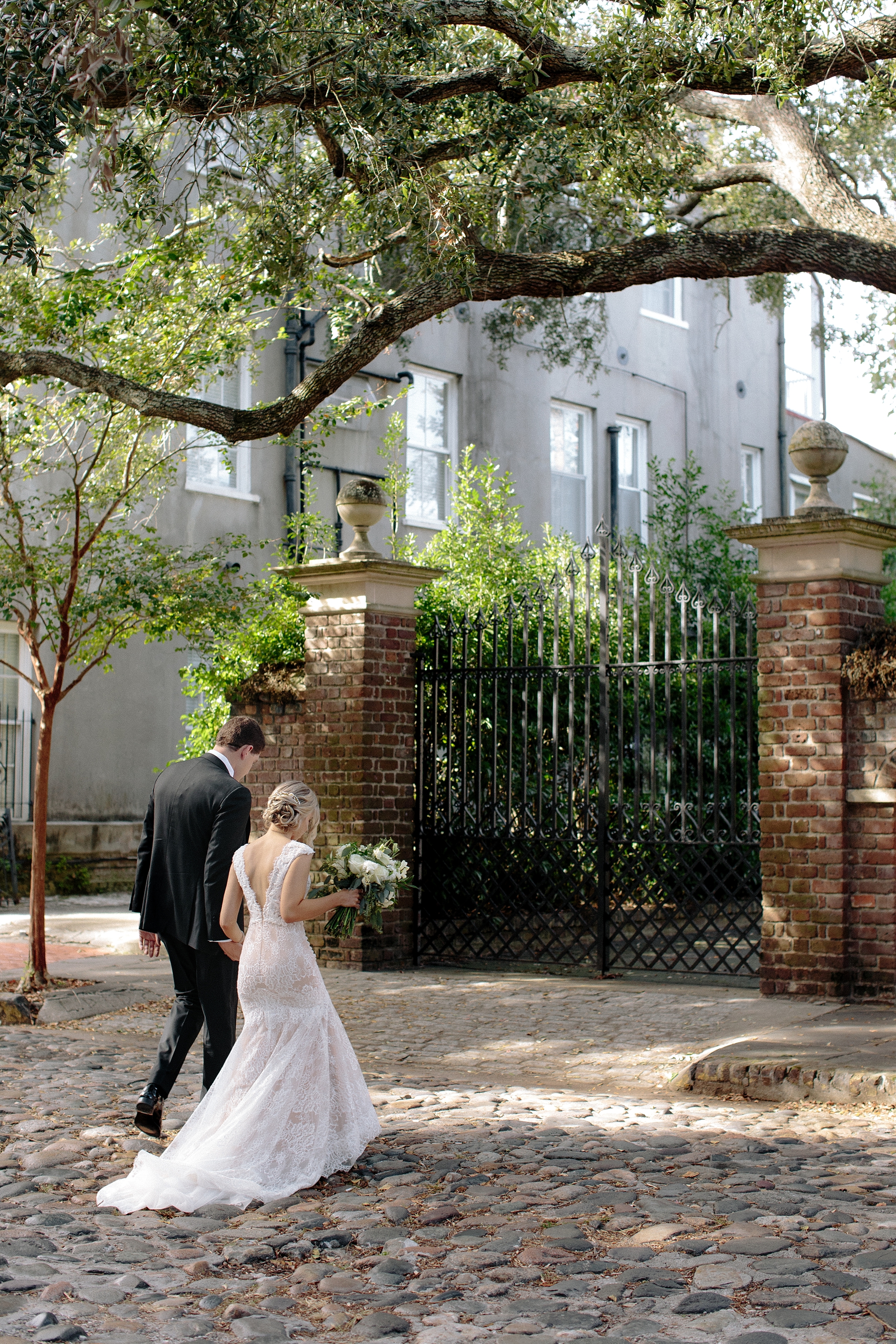 Bride and groom on cobblestone streets. Soft pink and teal blue romantic wedding in Historic Charleston, South Carolina by top Wedding Photographers Leigh and Becca.