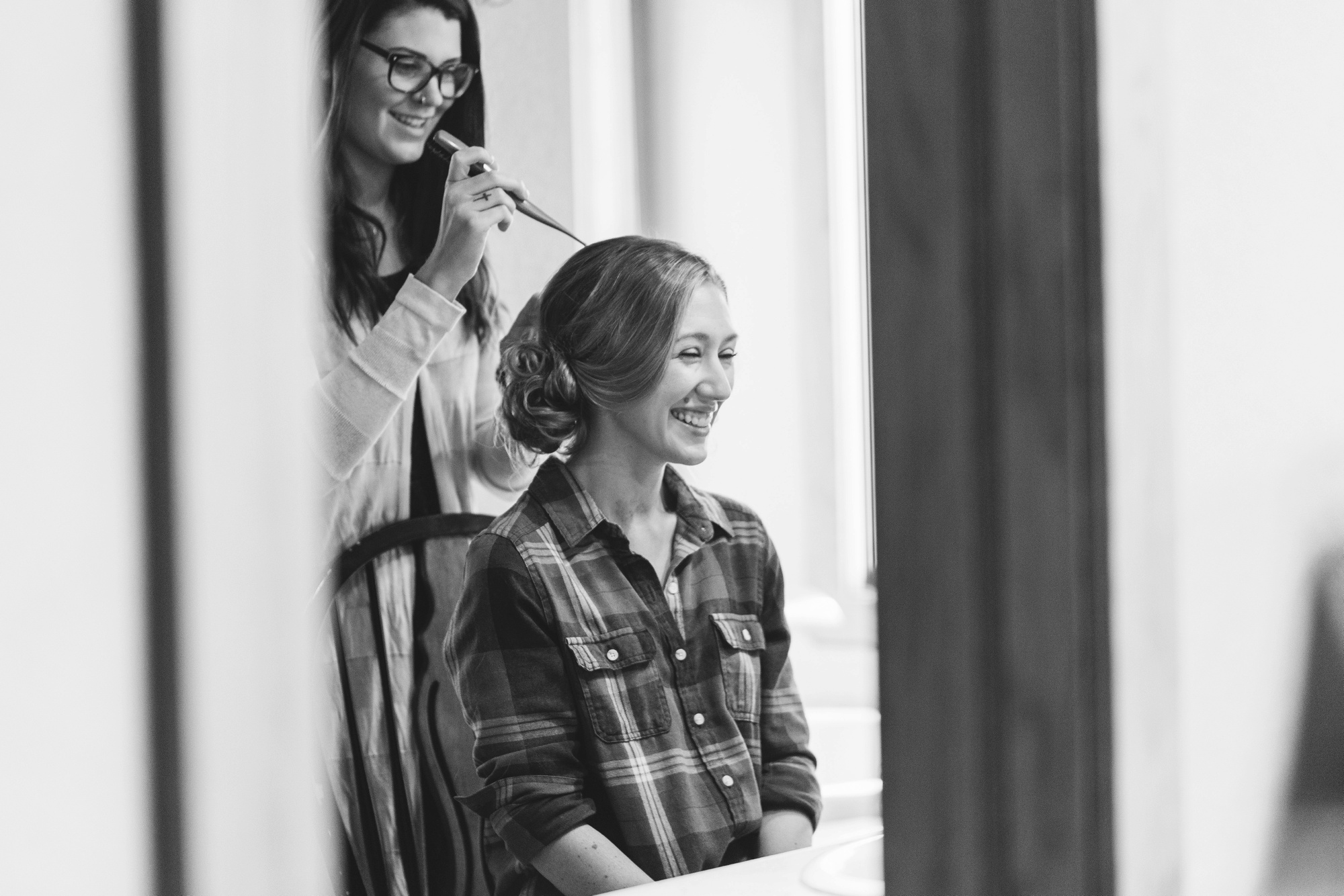 A care-free bride gets her hair done at her destination wedding in Dillon, Colorado. Photo by destination wedding photographer Rebecca Cerasani.