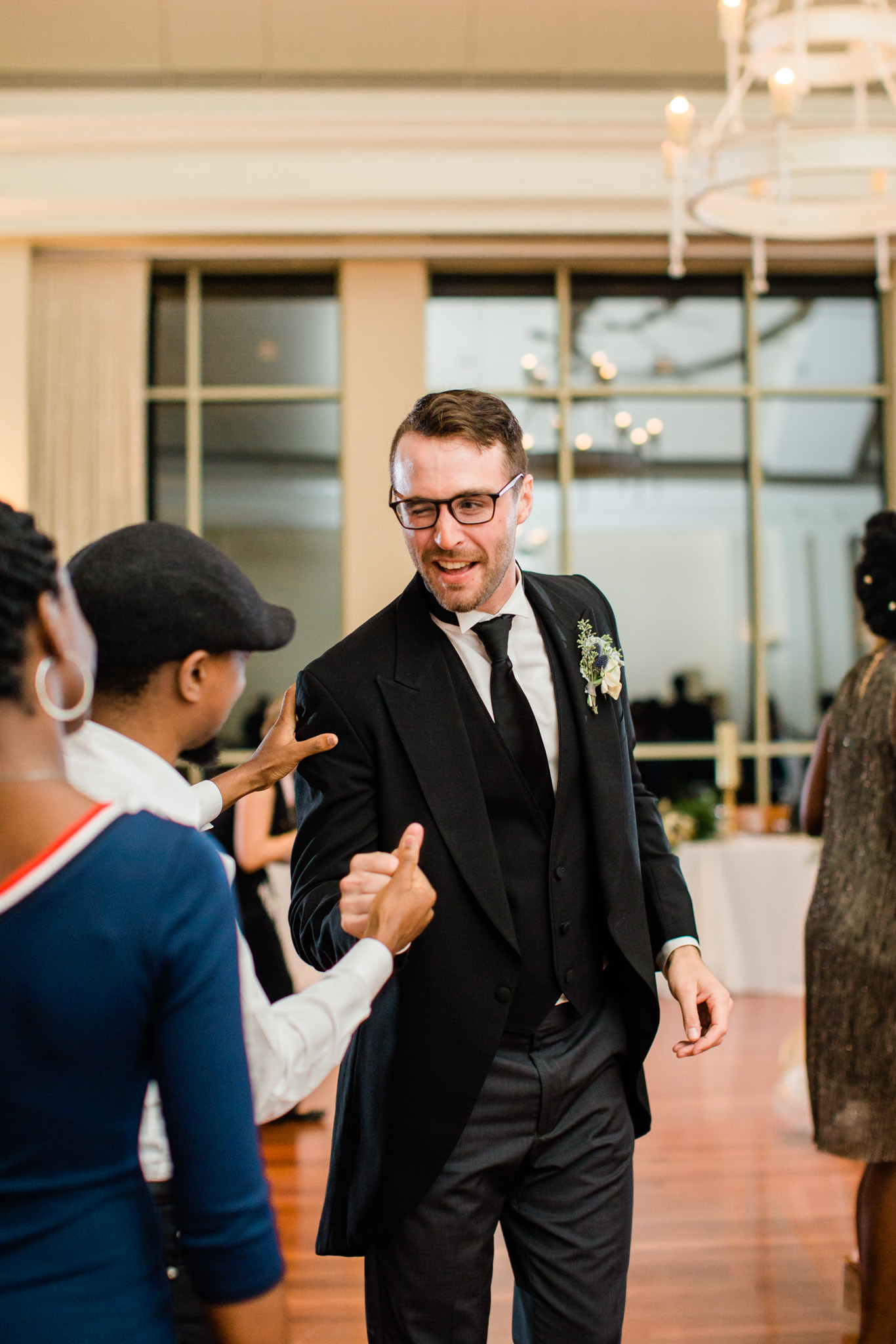 Groom winks while being congratulated by wedding guest. Top Atlanta wedding photographer Rebecca Cerasani