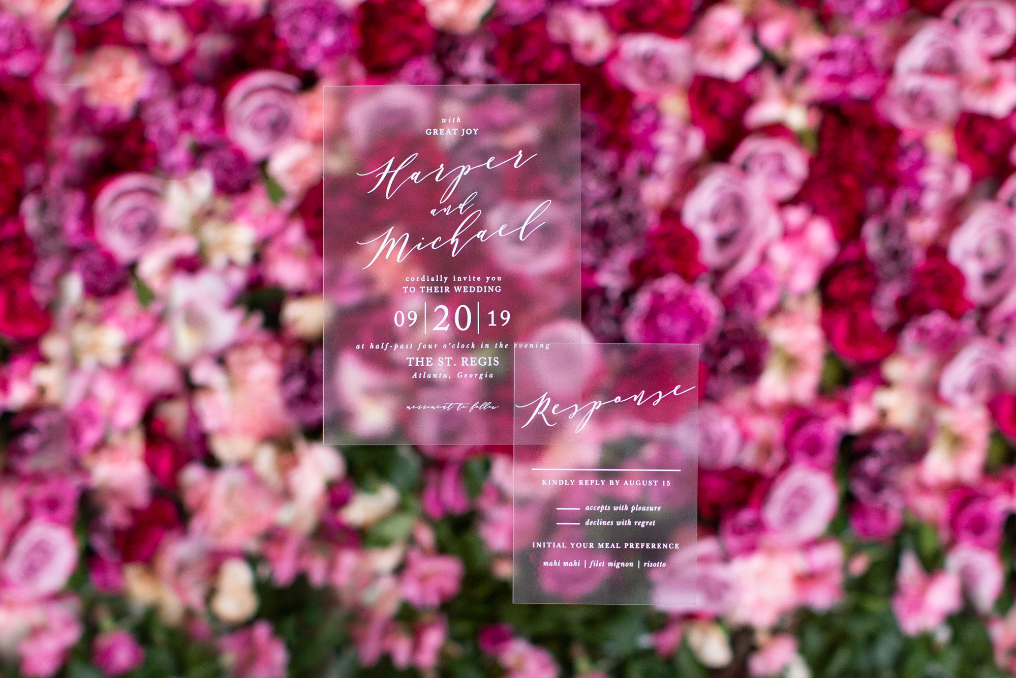 Custom clear wedding invitations against a pink flower wall. Does it get any better than this?