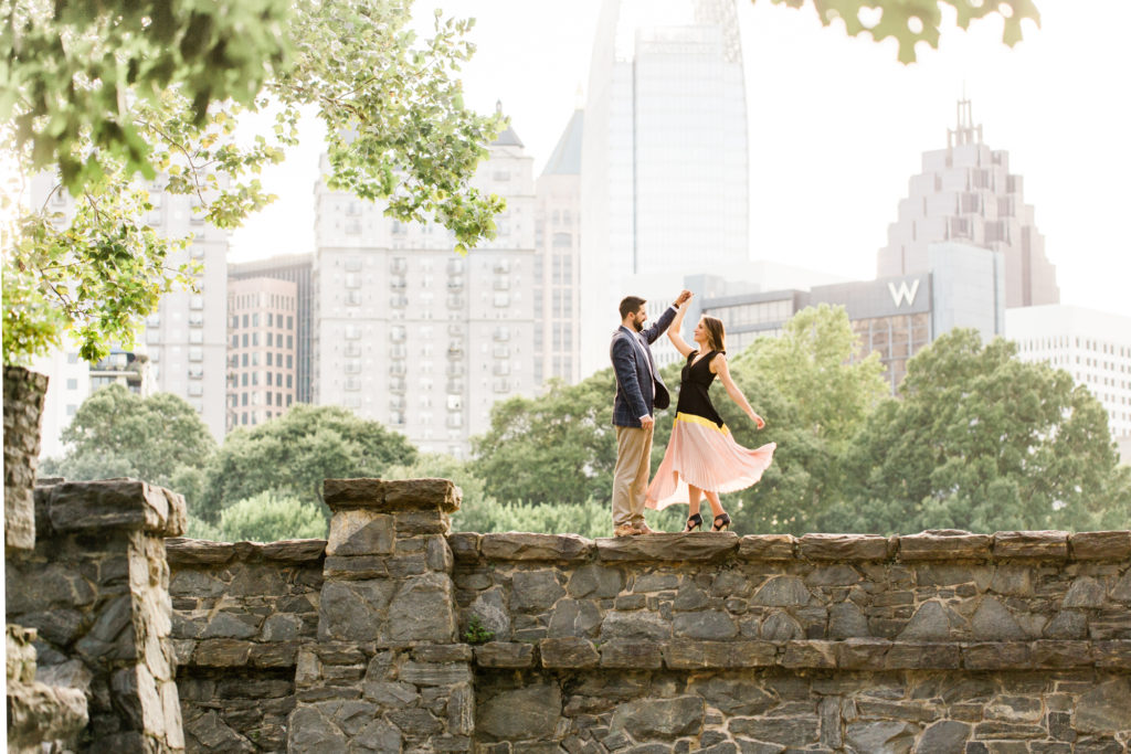 Couple dances in the sunlight at Piedmont Park with the Atlanta skyline as a backdrop