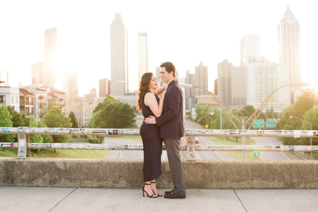 Engaged couple laughs during golden hour at Jackson Street Bridge